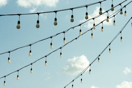 White economy light bulbs hanging in a row. Light bulbs view against the sky.の写真素材