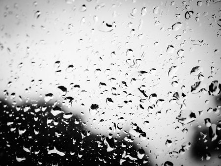 Black and white image of a wet glass. Stormy sky behind the wet glass.の写真素材