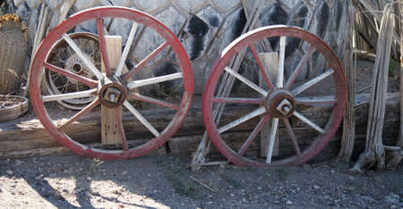 Old wagon wheels leanding against a wooden fence in Arizona,の写真素材