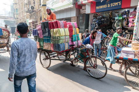 Man transporting cloths and fabrics on a cycle rickshaw through city of Dhaka, Bangladesh.