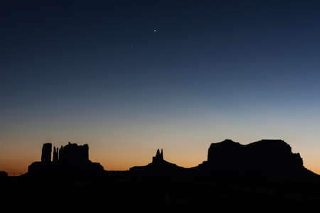 After Sunset and strong colors at the buttes in The Monument Valley, Navajo Indian tribal reservation park. Deep blue sky with cloudy and red sand dust in a rough plateauの写真素材
