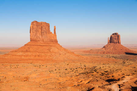 Sunset and strong colors at the buttes in The Monument Valley, Navajo Indian tribal reservation park. Deep blue sky with cloudy and red sand dust in a rough plateauの写真素材