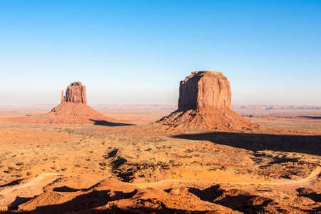 Sunset and strong colors at the buttes in The Monument Valley, Navajo Indian tribal reservation park. Deep blue sky with cloudy and red sand dust in a rough plateauの写真素材