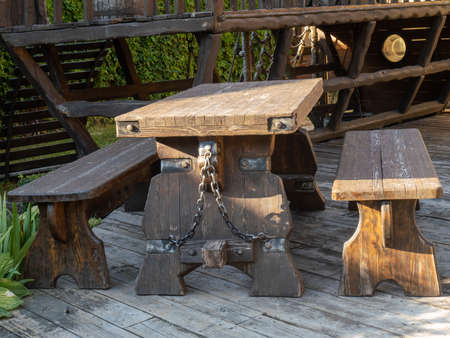 A wooden table and two long benches are tied to the table with a chainの写真素材