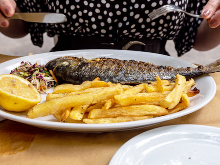 Grilled fish with lemon on plates with fried potatoes. high quality photoの写真素材