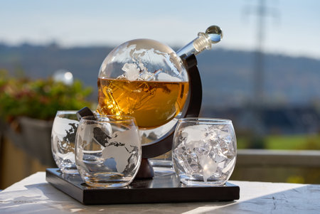 Bartender pours whiskey from a decanter into a globe glass filled with ice, creating a visually appealing displayの写真素材