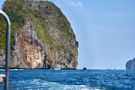 Impressive stone cliffs meet the vibrant turquoise waters of the thai seaの写真素材