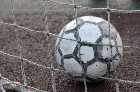 old shabby ball into the goal on the artificial turf