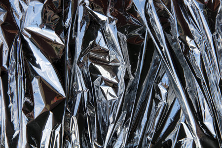 crumpled foil shiny silver background with glare and reflections