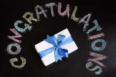 gift in celebratory packing on a background of the inscription congratulationsの写真素材