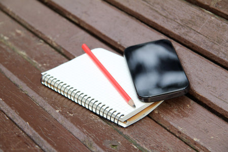 note pad and smartphone are on the bench