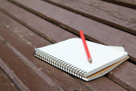 sketchbook and a pencil lying on a wooden bench