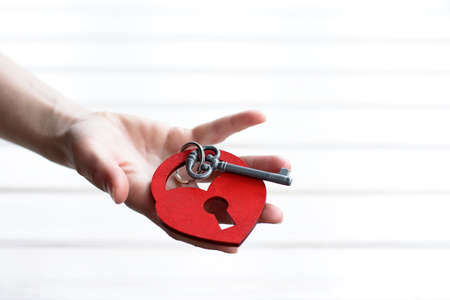 red wooden heart-shaped lock with a key on the handの写真素材