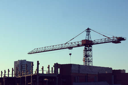 construction crane towers over the construction site in the evening at sunsetの写真素材