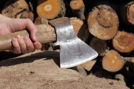 man holding the ax in his hand on a background of chopped firewoodの写真素材
