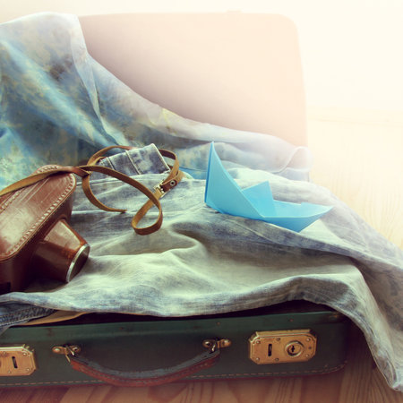 retro background old suitcase with a camera and a paper boat / weekend travel time