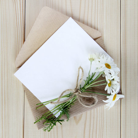 bouquet of wild daisies with an envelope and a card to wish a top view / festive flower letter