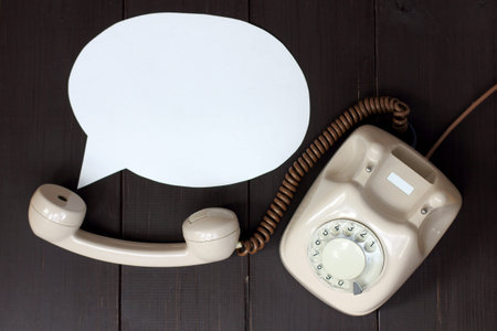 retro phone and the concept of the voice coming out of the tube lying on a wooden table top view /...