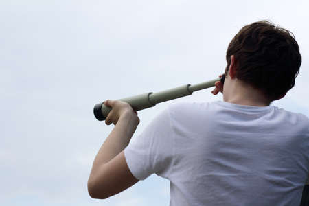 young man looks into the distance across telescope approximating / vision of futureの写真素材