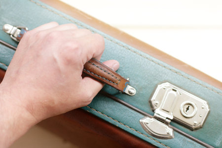 human hand holds the handle of the suitcase retro top view / travel with a suitcase in hand