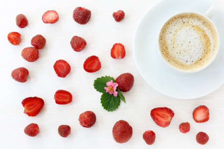 flat lay with red strawberries and frothy coffee on light wooden background top view / coffee strawberry backgroundの写真素材