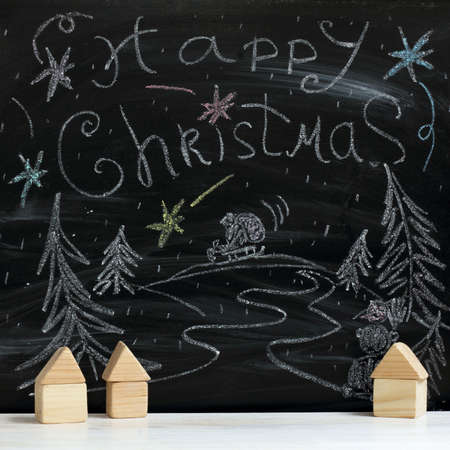 Wooden houses on the background of a winter landscape painted by with chalk on blackboard / fairytale Christmas night in the villageの写真素材