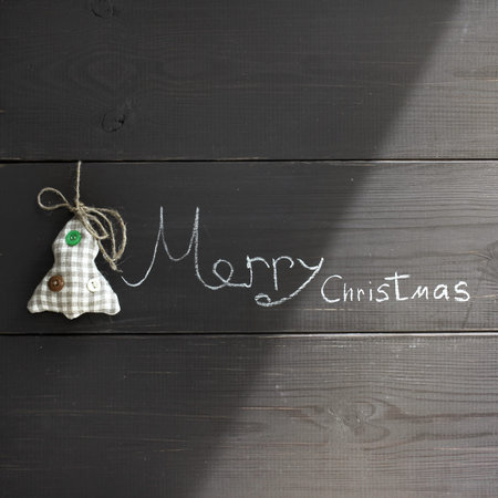 toy holiday tree and an inscription Merry Christmas made with chalk on a wooden background / upcoming festive eventの写真素材