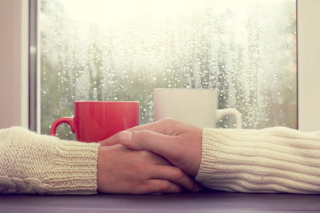 couple people at a table, with the care relate to each other in the rain outside the window / warm...