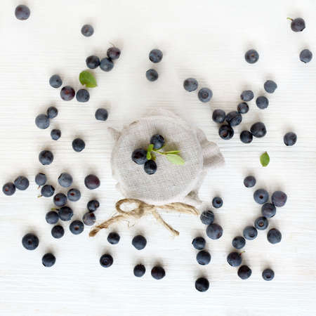 flat layout with a jar of jam and blueberries scattered around on the table top view / summer forest berriesの写真素材