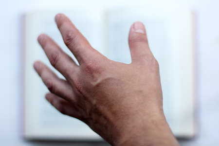 blurs the shape of a hand stretching to the a book in the background / thirst for knowledgeの写真素材