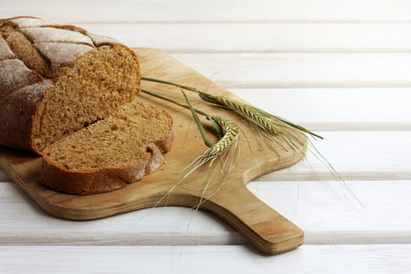 sliced dark bread lying on cutting wooden board, decorated with spikelet / traditional Russian dish