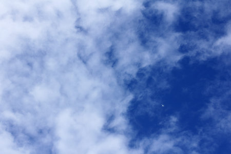 small plane silhouette in the clouds against the blue sky view from below / travel by plane
