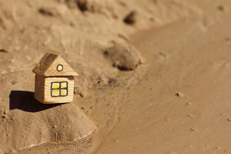 small wooden house standing on a sandy landscape under a blazing sun / hot days of global warmingの写真素材