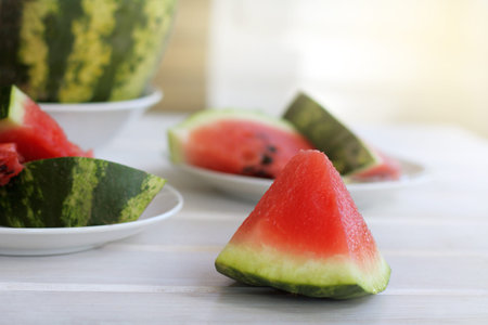 red slices of ripe watermelon lie on a light table / juicy sweet dessert