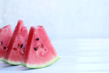 Juicy slices of ripe watermelon lie on luminous lights background / sweet dessert for the holidayの写真素材