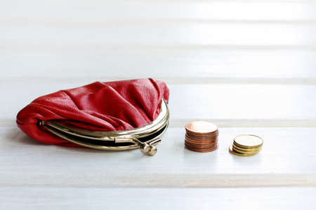 red retro purse and a stack of of coins on a light wooden background / money saving storageの写真素材
