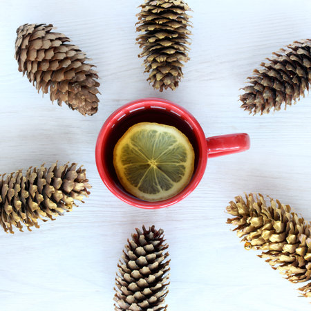 Tea with lemon in a red circle surrounded by cones / beverage with the aroma of Christmas trees