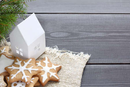 white house with cookies in the form of snowflakes, located under a green tree on a desk / atmosphere of the Christmas holidaysの写真素材