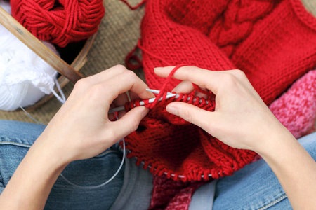hands knitting with red yarn, garments for the winter season / Warming hobbies home
