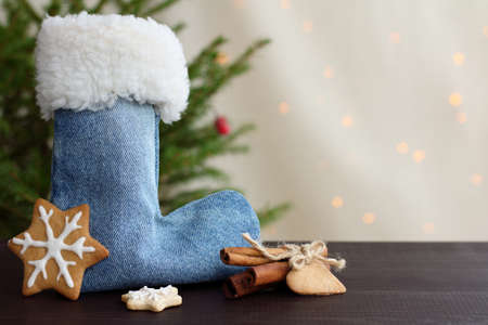 boot for gifts and cookies figure in the form of snowflakes under the Christmas tree, against a background of holiday lights / Christmas surprises and mysteriesの写真素材
