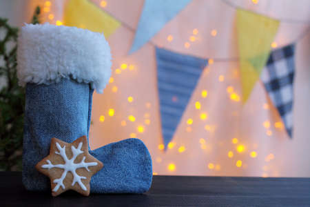 boot with red mug and ginger cookies stand under the Christmas tree, against a background of festive lights garlands / New Year atmosphere of the meetingの写真素材