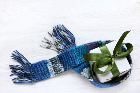 flat layout of a gift with a bow green, blue scarf in the top view / greeting with a warm hint