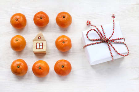 small toy house with tangerines and a gift on the table top view / concept home holiday atmosphereの写真素材