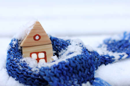 warming blue scarf around a wooden house in the winter season / when behind a window snow and coldの写真素材