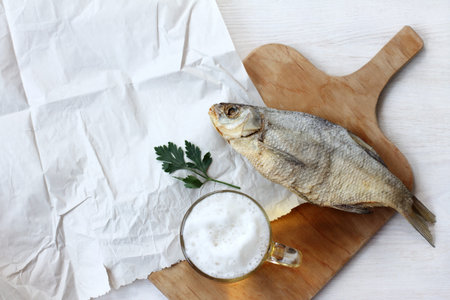 foamy beer in transparent mug and salted fish top view / still life with drinks and snacks