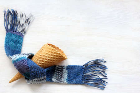 empty wafer cone in warm blue scarf on a light surface / tasty blank winter dessertの写真素材