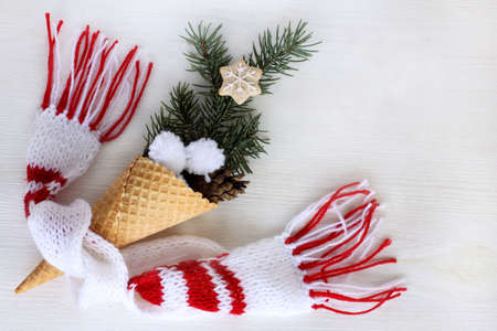 waffle cone with a branch of a Christmas tree, pine cones and cookies, wrapped in a warm scarf / concept festive ice creamの写真素材