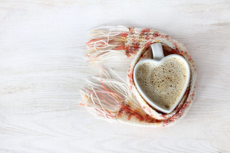 heart symbol in the form of a cup of coffee with foam wrapped in a warming scarf / aspiration good...