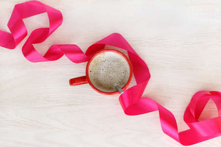 flat lay with red mug of frothy coffee and flowing ribbon top view / break with a delicate aroma of cappuccinoの写真素材