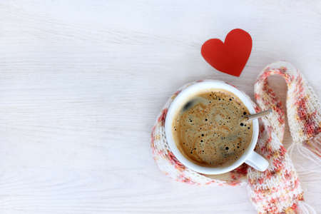 hot coffee in a mug wrapped a scarf, and a heart symbol, top view / favorite beverage warmsの写真素材